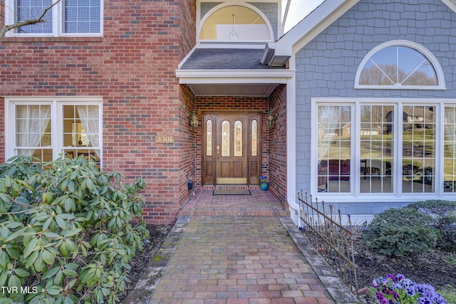 view of exterior entry featuring a shingled roof