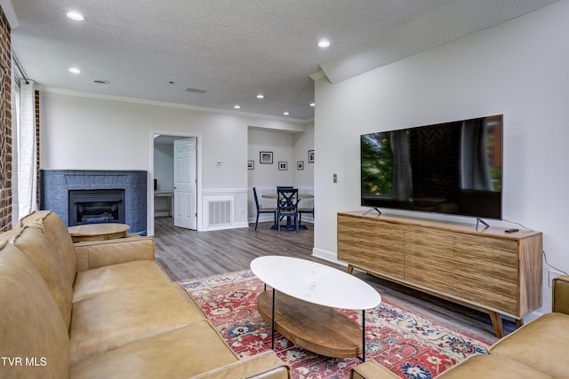 living room with visible vents, dark wood-style floors, ornamental molding, a textured ceiling, and a fireplace