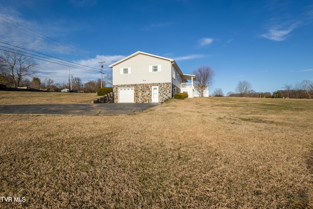 view of property exterior with driveway, stone siding, a garage, and a yard