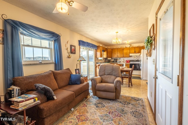 living room with a textured ceiling and ceiling fan with notable chandelier