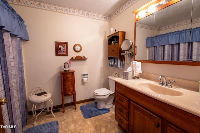 bathroom with toilet, baseboards, and vanity