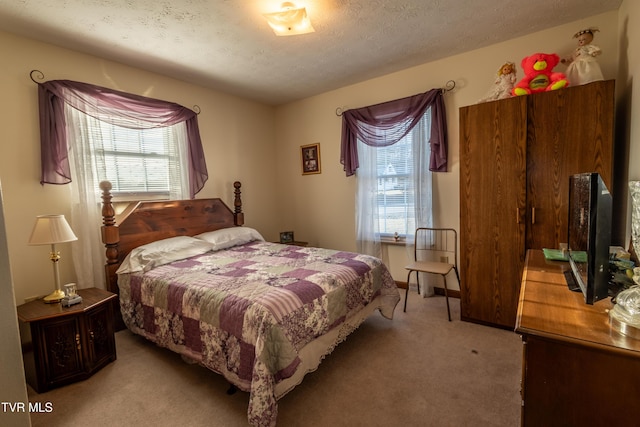 bedroom featuring multiple windows, a textured ceiling, and light colored carpet