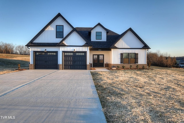 modern inspired farmhouse with french doors, brick siding, a shingled roof, a garage, and driveway