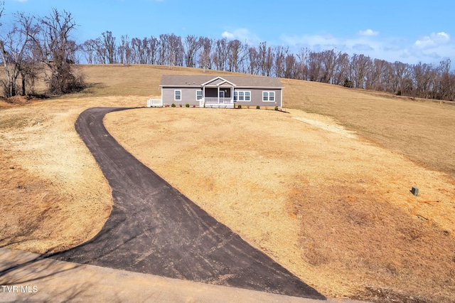 view of front of house featuring covered porch, driveway, and a front lawn