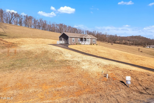 view of front facade featuring a rural view, driveway, and a front lawn