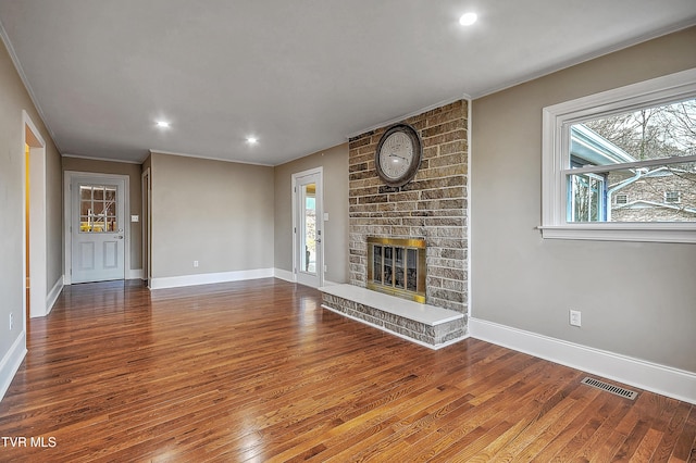 unfurnished living room featuring a fireplace, wood finished floors, visible vents, and baseboards