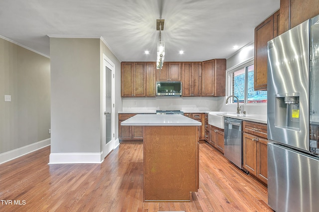 kitchen featuring a kitchen island, appliances with stainless steel finishes, light countertops, light wood-type flooring, and a sink