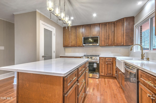 kitchen with appliances with stainless steel finishes, light wood-style floors, light countertops, and crown molding