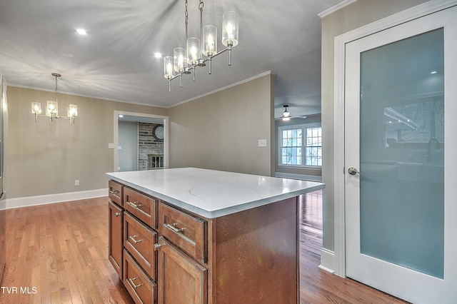 kitchen featuring ornamental molding, light wood-type flooring, brown cabinetry, and a kitchen island