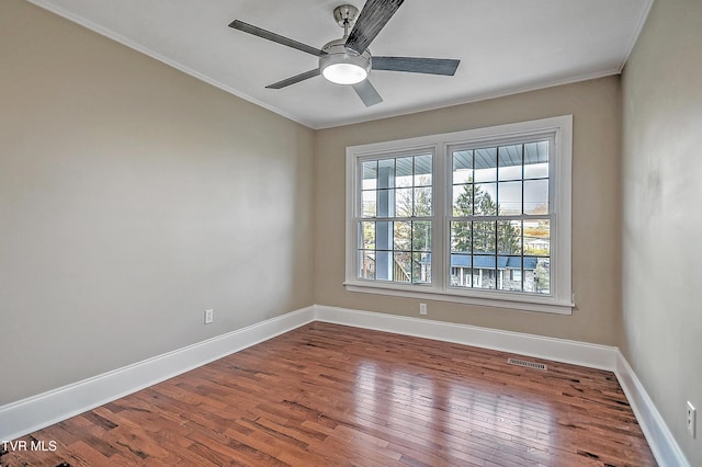 unfurnished room featuring ornamental molding, wood-type flooring, visible vents, and baseboards