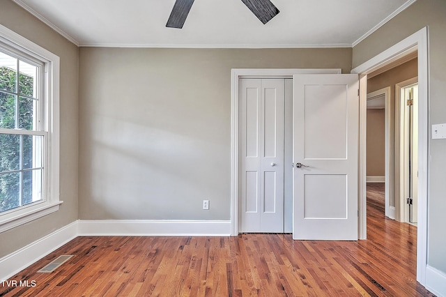 unfurnished bedroom with wood finished floors, visible vents, and multiple windows