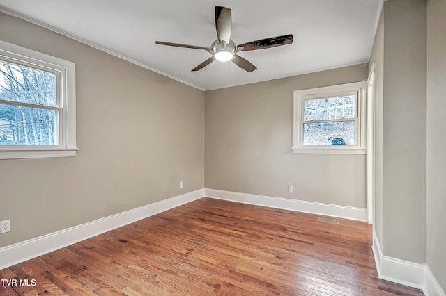 unfurnished room with visible vents, a ceiling fan, baseboards, ornamental molding, and wood-type flooring