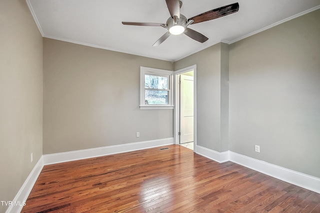 unfurnished room with wood-type flooring, visible vents, crown molding, and baseboards