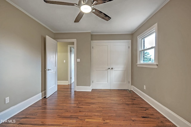 unfurnished bedroom featuring dark wood-style floors, ornamental molding, a closet, and baseboards