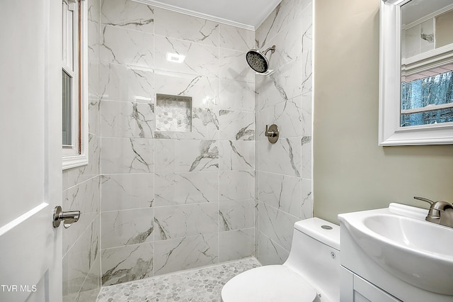 bathroom featuring toilet, tiled shower, and vanity