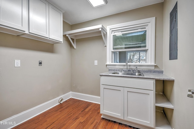 laundry room featuring dark wood finished floors, cabinet space, hookup for an electric dryer, a sink, and baseboards