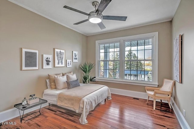 bedroom with baseboards, wood finished floors, a ceiling fan, and crown molding