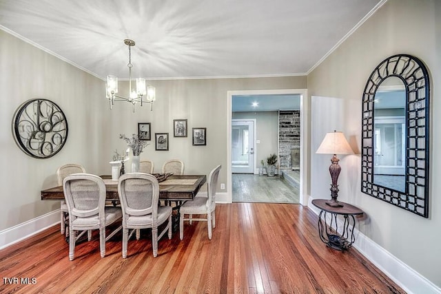 dining room with ornamental molding, a chandelier, baseboards, and wood finished floors