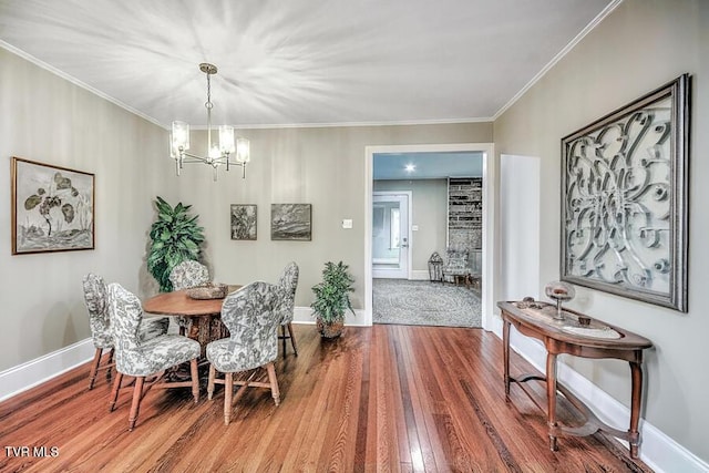 dining area with ornamental molding, a notable chandelier, baseboards, and wood finished floors