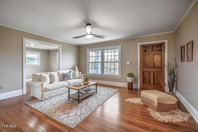 living room featuring crown molding, hardwood / wood-style floors, a ceiling fan, and baseboards