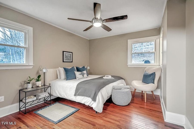 bedroom with ornamental molding, ceiling fan, baseboards, and wood finished floors