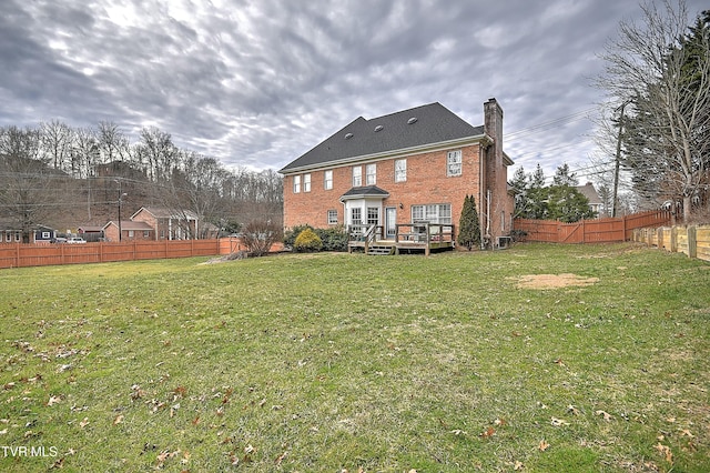 rear view of property featuring a wooden deck and a lawn