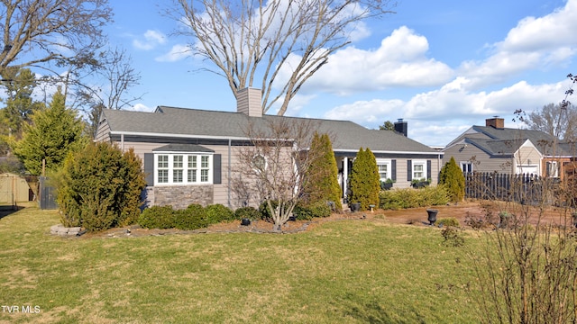 view of front of property featuring stone siding, a chimney, fence, and a front lawn