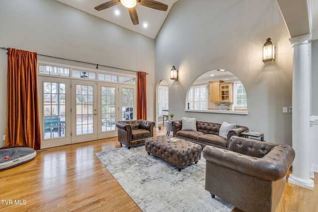 living area featuring high vaulted ceiling, light wood-type flooring, and ornate columns