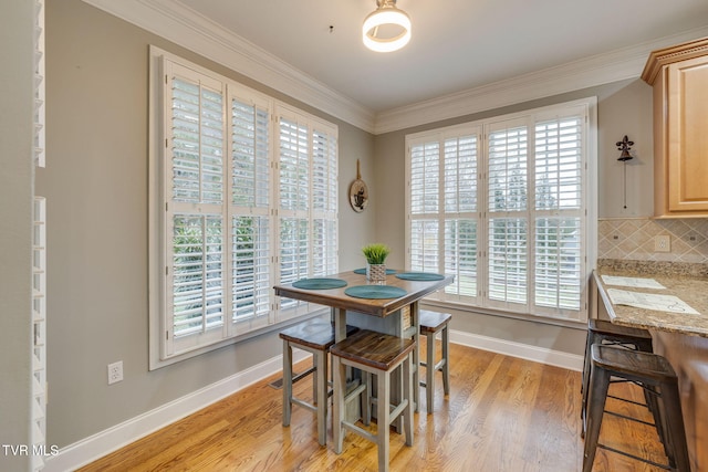 dining room featuring ornamental molding, light wood-style flooring, and baseboards