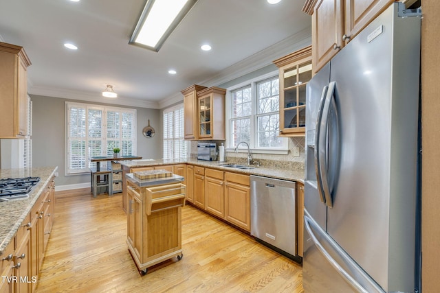 kitchen with a kitchen island, glass insert cabinets, light stone countertops, stainless steel appliances, and a sink