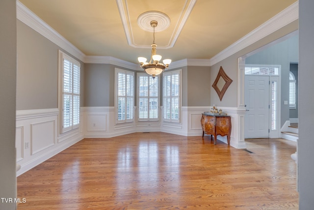 interior space featuring light wood-type flooring, crown molding, stairway, and an inviting chandelier