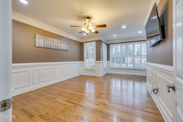 empty room with a ceiling fan, wainscoting, crown molding, light wood-type flooring, and recessed lighting