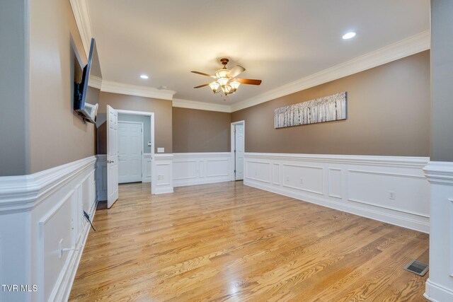 spare room with light wood-type flooring, crown molding, visible vents, and a ceiling fan