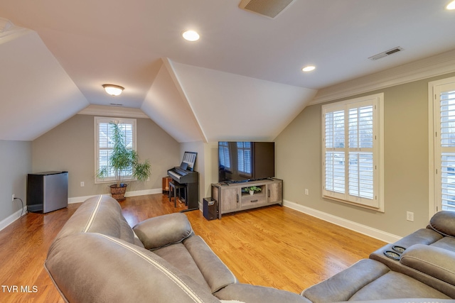 living room with lofted ceiling, visible vents, and wood finished floors