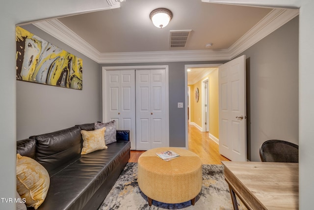 living area featuring light wood-style flooring, visible vents, and crown molding