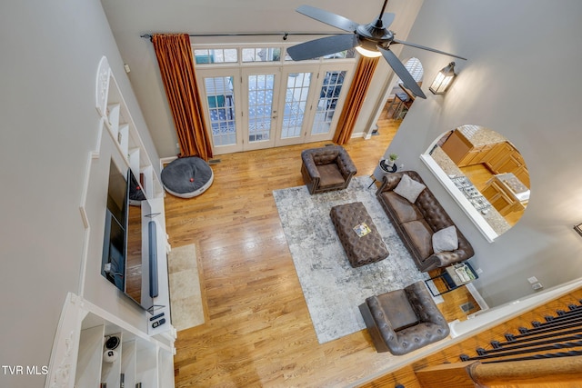 living room featuring french doors, ceiling fan, baseboards, and wood finished floors