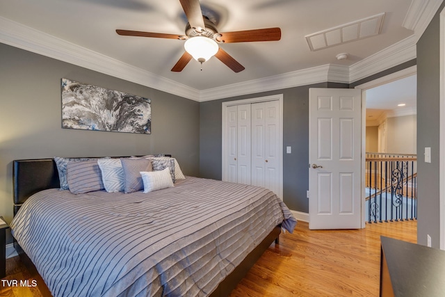 bedroom featuring visible vents, a closet, ornamental molding, and wood finished floors