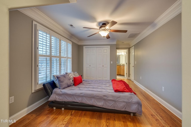 bedroom with baseboards, wood finished floors, visible vents, and crown molding