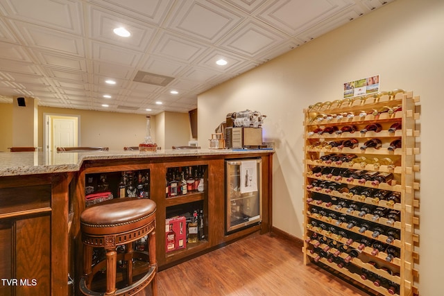 wine cellar with an ornate ceiling, a dry bar, recessed lighting, wood finished floors, and baseboards