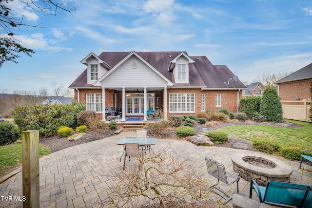 rear view of property with french doors, brick siding, a patio, ceiling fan, and a fire pit