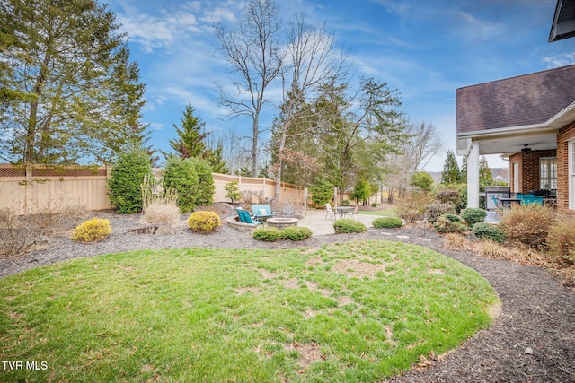 view of yard with an outdoor fire pit, a ceiling fan, a fenced backyard, and a patio