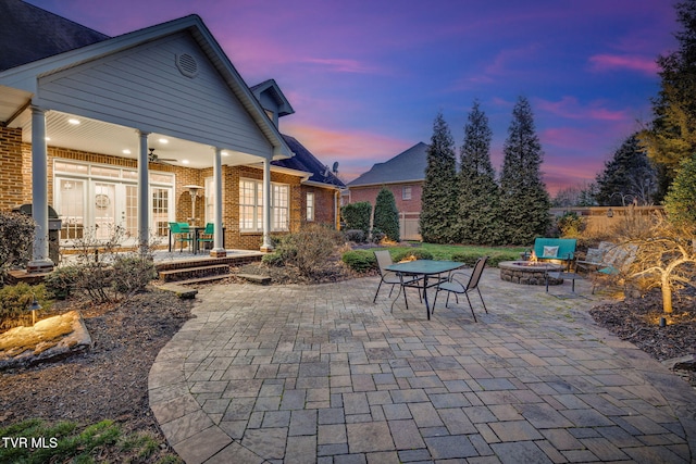 patio terrace at dusk with fence, a fire pit, and grilling area