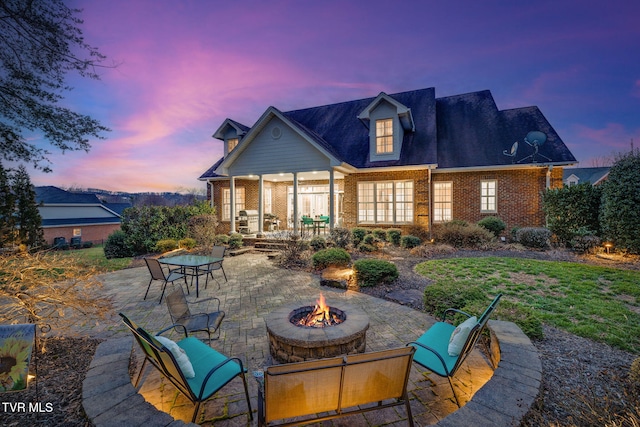 back of house with brick siding, a patio, and a fire pit