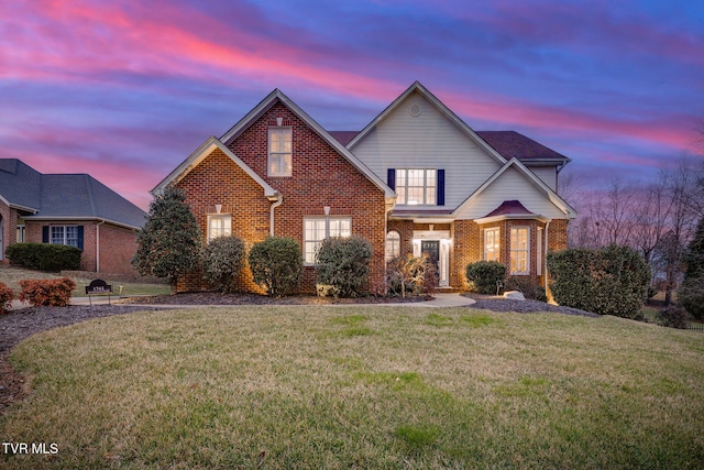 traditional-style house featuring a front yard and brick siding