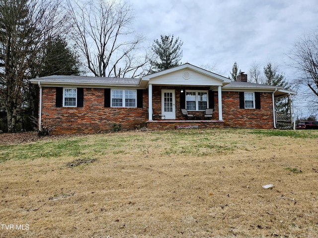 ranch-style house featuring covered porch and a front lawn