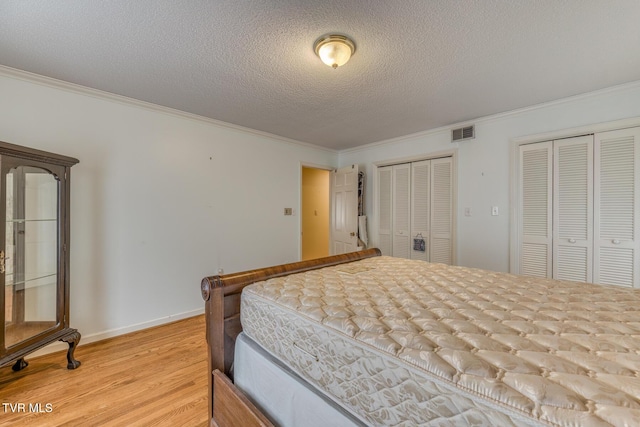305 Overbrook Dr, Bristol, TN 37620 - bedroom with light wood-style flooring, visible vents, crown molding, multiple closets, and a textured ceiling