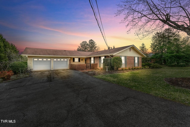 ranch-style home with brick siding, a yard, an attached garage, and driveway