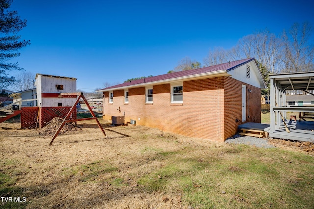 back of property featuring a deck, metal roof, brick siding, and cooling unit