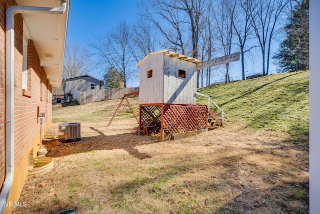 view of yard featuring cooling unit, fence, an outbuilding, and a storage unit