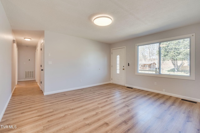 foyer with light wood-style floors, baseboards, and visible vents